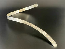 Load image into Gallery viewer, A sinuous braille neckpiece made of sterling silver. The braille dots along it read, "Beware; for I am fearless, and therefore powerful." The words "fearless" and "powerful" are accented in gold.