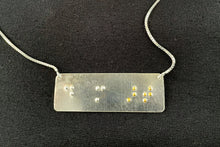 Load image into Gallery viewer, A functional, tactile braille necklace that reads "do more art" in grade 2 braille. The piece is bright, polished silver with the word "art" done in gold.