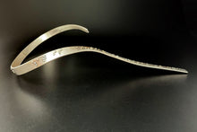 Load image into Gallery viewer, A curved silver neckpiece that wraps around the neck and then curves down the centerline of the chest. There is grade 2 braille on it, reading "It is only with the heart that one can see rightly; what is essential is invisible to the eye". The words "heart" and "essential" are done in gold.