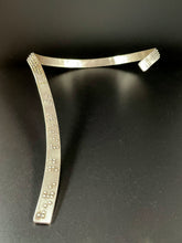 Load image into Gallery viewer, A curved silver neckpiece that wraps around the neck and then curves down the centerline of the chest. There is grade 2 braille on it, reading "It is only with the heart that one can see rightly; what is essential is invisible to the eye". The words "heart" and "essential" are done in gold.
