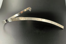Load image into Gallery viewer, A curved silver neckpiece, which wraps around the back of the neck before curving down over the centerline of the chest. Grade 2 braille on the piece reads "To love another person is to see the face of God". The word "God" is done in gold.
