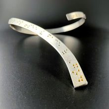 Load image into Gallery viewer, A curved silver neckpiece, which wraps around the back of the neck before curving down over the centerline of the chest. Grade 2 braille on the piece reads "To love another person is to see the face of God". The word "God" is done in gold.