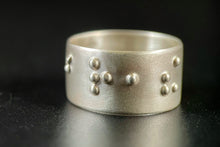 Load image into Gallery viewer, A sterling silver ring with a satin finish, which reads "breathe" in contracted, grade 2 braille.