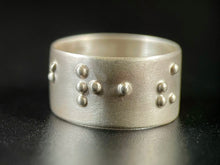 Load image into Gallery viewer, A sterling silver ring with a satin finish, which reads "breathe" in functional, contracted, grade 2 braille.