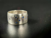 Load image into Gallery viewer, A thick, sterling silver ring with a random scattering of flush-set sapphires.
