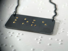 Load image into Gallery viewer, A functional, tactile braille necklace that reads "love" in grade 2 braille. The piece is dark, oxidized silver with gold dots.