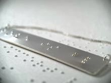 Load image into Gallery viewer, A sterling silver necklace that reads "love is blind" in contracted, grade 2 braille. The dots for the word "blind" are done in gold.