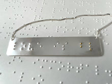 Load image into Gallery viewer, A sterling silver necklace that reads "love is blind" in contracted, grade 2 braille. The dots for the word "blind" are done in gold.