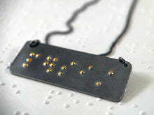 Load image into Gallery viewer, A dark, oxidized silver piece that reads "persist" in grade 2 contracted braille. The dots are done in gold.