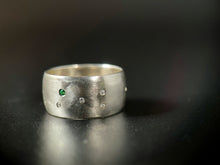 Load image into Gallery viewer, A sterling silver ring with a random scattering of flush set white moissanite stones and a single flush-set emerald.