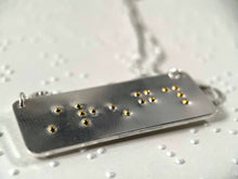 Load image into Gallery viewer, A sterling silver necklace with the word "strength" written in contracted, grade 2 braille. The dots are done in gold.