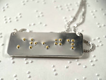 Load image into Gallery viewer, A sterling silver necklace with the word "strength" written in contracted, grade 2 braille. The dots are done in gold.