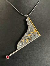 Load image into Gallery viewer, A triangular pendant, hanging askew. It is framed on two sides, one in gold covered wire, and one in silver. At the end of the framing silver wire is a lab grown ruby. The body of the pendant is reticulated silver, with a rough, organic texture. Small pools of gold are hidden in the crevices.
