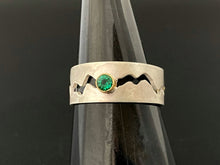 Load image into Gallery viewer, A sterling silver ring with a winding gap running down the middle of the band. There is a lab-grown round emerald in an 18k yellow gold setting in the middle of the gap.
