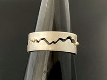 Load image into Gallery viewer, A sterling silver ring with a winding gap running down the middle of the band. Small dots of 18k yellow gold sit in the middle of the gap as spacers.
