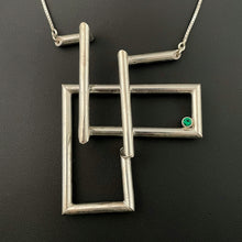 Load image into Gallery viewer, A twist of silver tubing set at right angles, overlapping itself in a double L shape. In the right-hand corner is a lab grown bright green emerald.
