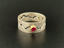 Load image into Gallery viewer, A sterling silver ring with a winding gap running down the middle of the band. There is a lab-grown round ruby in an 18k yellow gold setting in the middle of the gap. Gold spacers are visible in the back of the ring, holding the gap space open.
