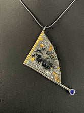 Load image into Gallery viewer, A triangular pendant, hanging askew. It is framed on two sides, one in gold covered wire, and one in silver. At the end of the framing silver wire is a lab grown purple sapphire. The body of the pendant is reticulated silver, with a rough, organic texture, with a smooth, flowing portion in the middle. Small spots of gold are nestled in the crevices.
