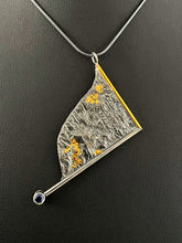 Load image into Gallery viewer, A triangular pendant, hanging askew. It is framed on two sides, one in gold covered wire, and one in silver. At the end of the framing silver wire is a lab grown blue sapphire. The body of the pendant is reticulated silver, with a rough, organic texture. Small pools of gold are hidden amongst the crevices.
