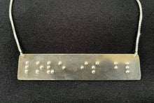 Load image into Gallery viewer, A necklace that reads &quot;love is blind&quot; in grade 2 braille. The piece is bright, polished silver.

