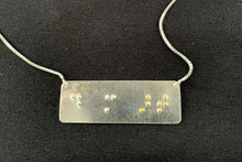 Load image into Gallery viewer, A functional, tactile braille necklace that reads &quot;do more art&quot; in grade 2 braille. The piece is bright, polished silver with the word &quot;art&quot; done in gold.
