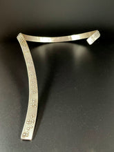 Load image into Gallery viewer, A curved silver neckpiece that wraps around the neck and then curves down the centerline of the chest. There is grade 2 braille on it, reading &quot;It is only with the heart that one can see rightly; what is essential is invisible to the eye&quot;. The words &quot;heart&quot; and &quot;essential&quot; are done in gold.
