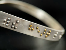 Load image into Gallery viewer, A close up of some of the braille in this silver neckpiece. The visible braille reads &quot;with the heart&quot; and the word &quot;heart&quot; is done in gold. The rest of the piece fades out of focus.
