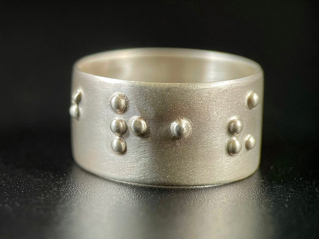 A sterling silver ring with a satin finish, which reads 