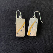 Load image into Gallery viewer, Rectangular silver earrings. This side of them is textured silver with similar but not identical gold arcs. Below the arcs there is a line of 3 lab-grown sapphires that match the flow of the gold. 
