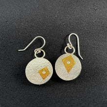 Load image into Gallery viewer, A set of round earrings. This side is textured silver. The lefthand earring has an irregular 4-sided shape in gold, while the right hand earring has a smaller, almost square 4 sided shape. In the center of each is a small, bright, round moissanite stone.
