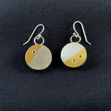 Load image into Gallery viewer, On this side of the earrings, the round earrings each have about 1/3 in a slanted angle, done in gold. On the left earring this is the upper left third, on the other earring it is the lower right third. Within this gold portion, the left earring has a single lab-grown sapphire, and the earring on the right has two.
