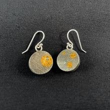 Load image into Gallery viewer, his side of the round earrings are textured darkened oxidized silver. The earring on the left has 3 circles of gold in different sizes and a moissanite stone. The earring on the right has a single larger gold circle with a moissanite stone set within it.

