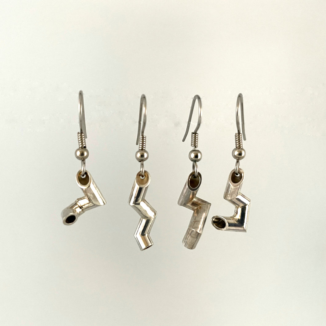 Four earrings hanging side by side. Each is made of sterling silver tubing bent at sharp angles into an interesting shape. No two are the same.