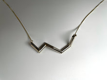 Load image into Gallery viewer, A necklace of sterling silver tubing, in a zigzag shape.

