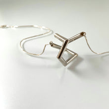 Load image into Gallery viewer, A necklace made of silver tubing that turns at sharp angles, twisting back on itself.
