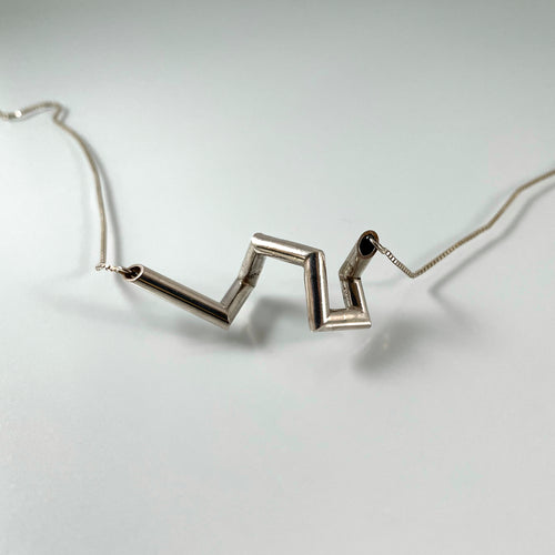 A necklace of sterling silver tubing, with sharp angles in a vague curl shape.