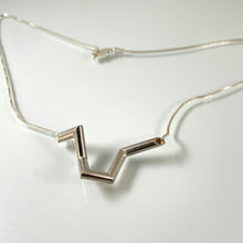 Load image into Gallery viewer, A necklace made of silver tubing, with sharp turns and twists. The overall shape is vaguely like the top of a heart.
