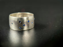 Load image into Gallery viewer, A thick, sterling silver ring with a random scattering of flush-set sapphires.
