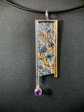 Load image into Gallery viewer, A rectangular silver necklace, handing vertically. The silver is textured in a terrain-like pattern. The necklace is framed on the top and sides in wire - gold on the right side, the rest in silver. Both side wires continue below the body of the piece, moreso on the left side, which also terminates in a lab-grown purple sapphire. There are several nearly connected  pools of gold in some of the recessed portions of the texture.
