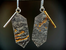 Load image into Gallery viewer, A pair of earrings, in the shape of rectangles, but with pointed ends, hanging vertically. Each top outside edge has a wire border that hangs off the edge of the body  of the earring. The wire on the left is silver and the right is gold. The body of the earrings has a reticulated, terrain-like texture. The left earring has three horizontal bars of gold of different lengths, and the right earring has some scattered spots of gold in the recessed portions.
