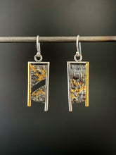 Load image into Gallery viewer, A rectangular pair of earrings, hanging vertically. The top and both sides are framed in wire - silver on the top and inside edge, gold on the outside. The silver wire on each earring hangs lower, with the gold dropping a short way below the edge of the rectangle. The center of the rectangle is reticulated silver, in a textured, terrain-like pattern. The left earring has a gap in the main portion, running diagonally from upper right to lower left. Both earrings have gold in the recessed portions.
