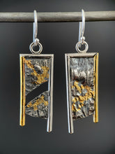 Load image into Gallery viewer, A rectangular pair of earrings, hanging vertically. The top and both sides are framed in wire - silver on the top and outside edge, gold on the inside. The outside border on each earring hangs lower, with the inside dropping just below the edge of the rectangle. The center of the rectangle is reticulated silver, in a textured, terrain-like pattern. The left earring has a gap in the main portion, running diagonally upper left to lower right. Both earrings have gold in the recessed portions.
