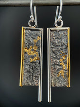 Load image into Gallery viewer, The other side of these earrings. A rectangular pair of earrings, hanging vertically. The top and both sides are framed in wire - silver on the top and inside edge, gold on the outside edge. The inside border on each earring hangs lower, with the outside dropping just below the edge of the rectangle. The center of the rectangle is reticulated silver, in a textured, organic, terrain-like pattern. There are veins of gold running in a twisting pattern through the recessed parts.
