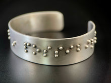 Load image into Gallery viewer, A sterling silver cuff bracelet, with accurately sized, spaced, and contracted braille. The portion that can be seen reads &quot;in possibil&quot;.
