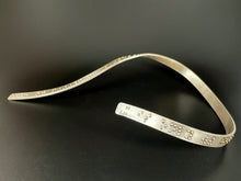 Load image into Gallery viewer, A curved silver neckpiece that warps around the neck and curves down the chest. The visible curve around the neck has functional, contracted grade 2 braille that reads &quot;It is only with the heart&quot; before it curves out of sight of the photograph. The word &#39;heart&#39; is done in gold.
