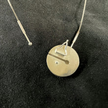 Load image into Gallery viewer, An example of a keyhole clasp. This shows the back of a round pendant, with a slit and safety catch for working the  clasp. One end of the chain is permanently attached to the pendant, the other is a &#39;key&#39; with a stout piece of wire with a ball on the end, which can be inserted into the slot at one end, and then slides down and locks into place.
