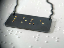 Load image into Gallery viewer, A functional, tactile braille necklace that reads &quot;love&quot; in grade 2 braille. The piece is dark, oxidized silver with gold dots.
