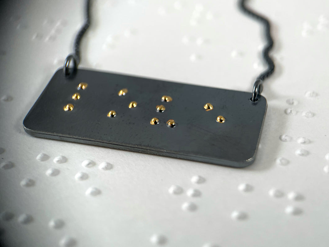 A functional, tactile braille necklace that reads 