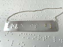 Load image into Gallery viewer, A sterling silver necklace that reads &quot;love is blind&quot; in contracted, grade 2 braille. The dots for the word &quot;blind&quot; are done in gold.
