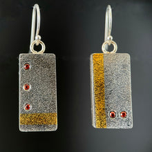 Load image into Gallery viewer, Rectangular earrings in textured silver. The earring on the left has a vertical stripe of gold near the edge, with two small orange sapphires in a horizontal line near the bottom. The earring on the right is the reverse - has a line of 3 orange sapphires arranged in a vertical line with a horizontal line in gold near the bottom.
